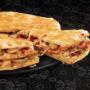 Three layers of a large Sweet Chilli Chicken Triple-Decker® placed on top of a black plate, on a black background, with shape patterns.