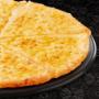 Large vegetarian Margherita pizza from Debonairs Pizza placed on top of a black plate, on a black background, with shape patterns.