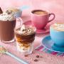 Milky Lane Double Thick milkshakes in strawberry and banana flavour on a grey surface with against a blue background.