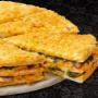 Large Vegetable Triple-Decker® pizza from Debonairs Pizza placed on top of a white plate, on a black background, with shape patterns.